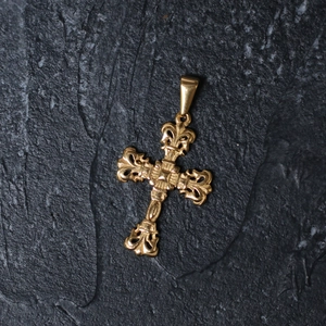 Detailed macro view of a vintage gold-plated titanium steel cross pendant on stone