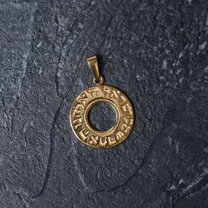 Detailed macro view of a gold-plated titanium circular pendant with Hebrew engraving