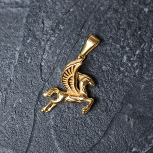 Macro shot of gold-plated pegasus pendant showing detailed wing texture on stone background