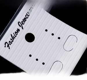 Macro shot of white jewelry display card featuring thick embossed vertical stripe texture