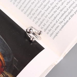 Detailed view of silver minimalist bead open ring displayed on an open book page