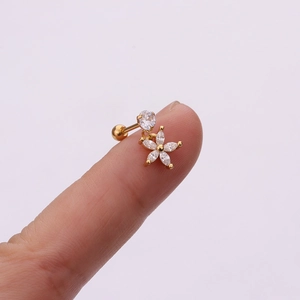 Macro view of gold flower cartilage stud with marquise zircon held on fingertip
