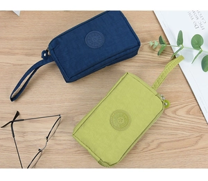 Pochette in nylon con tre cerniere e logo sportivo su superficie in legno naturale