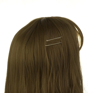 Gros plan de pinces à cheveux dorées à texture torsadée sur cheveux châtains