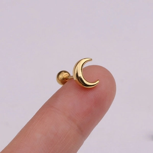 Golden crescent moon stud earring with ball back shown on fingertip for size reference