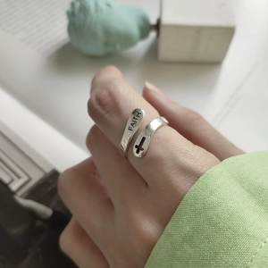Detail of 925 sterling silver ring with FAITH engraving and cross cutout on a finger