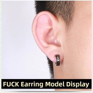 Close-up of black punk clip-on earring with white FUCK lettering detail on a model