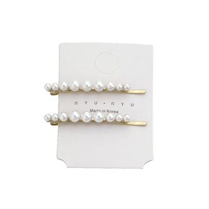 Elegant gold metal hair clips set with gradient white pearls on a white display card