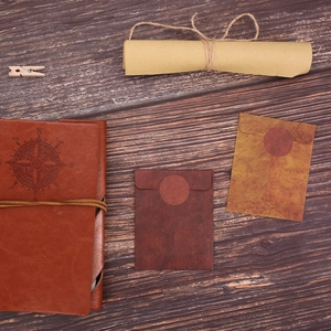 Vintage red-brown leather notebook with compass pattern and kraft envelopes on wood