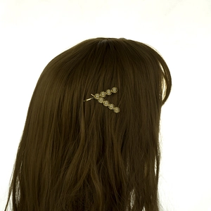 Detail of golden V-shaped daisy hair clip with small diamonds worn on hair