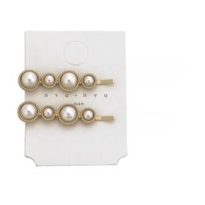 Close-up of golden hair clips with white pearls, measuring 4.8cm length and 10g weight
