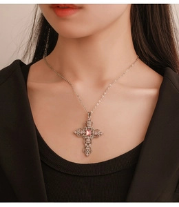 Detail of vintage silver cross necklace with pink gemstones worn on a female model