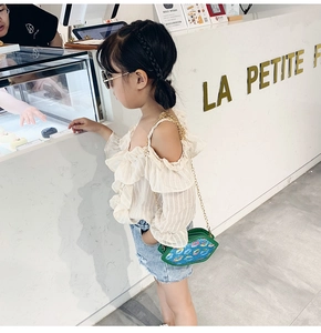 Detailed view of girls summer outfit with ruffled top and denim shorts in a cafe