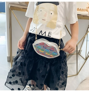 Detailed view of child wearing a colorful lip pattern crossbody bag with gold chain strap