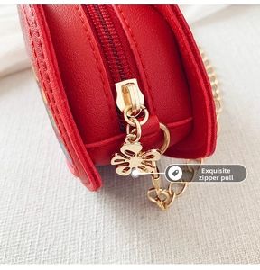 Macro detail of golden flower zipper and chain strap on red leather crossbody bag