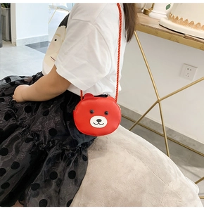 Detail of red bear-shaped kid's crossbody bag featuring PU leather and woven strap
