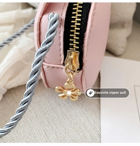 Close-up of pink leather kid bag with golden flower zipper and blue woven strap
