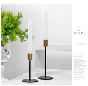 Detail of modern black and gold metal candlesticks with white candles in a Nordic setting