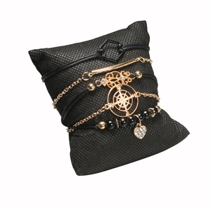 Detailansicht des fünfteiligen Armband-Sets mit Kompass-Herz-Anhängern auf schwarzem Kissen