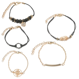Detailset aus fünf gold-schwarzen Bettelarmbändern mit Herz- und Hexagon-Anhängern
