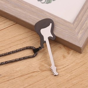 Detailed close-up of a black and white guitar pendant necklace on a natural wooden desk
