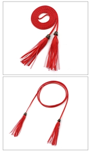 Detail of red braided waist chain belt with tassel accents and metallic buckle on white background