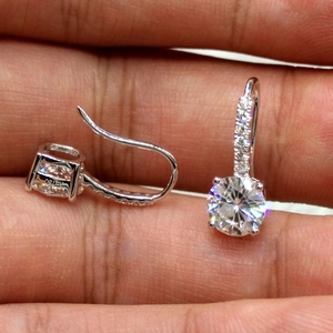 Macro view of round cut zircon earrings featuring Au750 hallmark and silver prongs