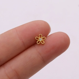 Macro shot of rose gold flower earring with central zircon displayed on a finger