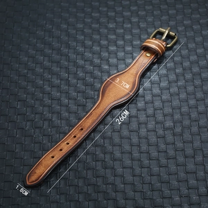 Dettaglio del cinturino in pelle marrone vintage con fibbia in ottone su sfondo nero
