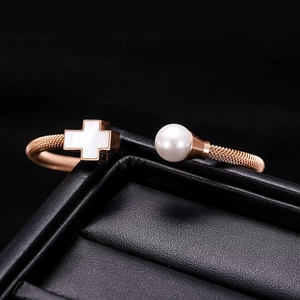 Detailansicht eines roségoldenen Kabelarmbands mit Perle und weißem Kreuz-Inlay