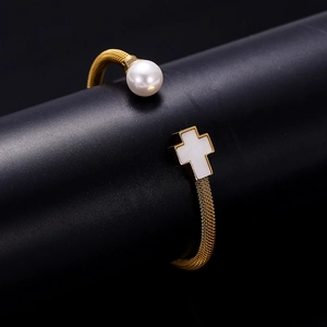 Goldener offener Armreif mit weißer Perle und Emaille-Kreuz auf schwarzem Grund