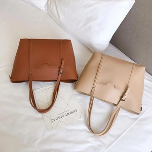 Detail of minimalist brown and beige large capacity PU leather tote bags on white bedding