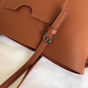 Detailed macro view of brown leather texture and precision stitching on women's tote bag