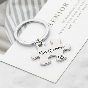Detailopname van de zilveren puzzel sleutelhanger met His Queen gravure en hartjes