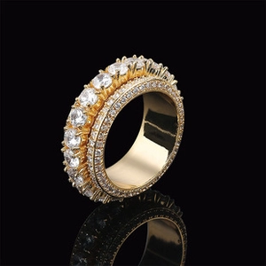Macro side view of golden ring with multi-row round clear zircons on black background