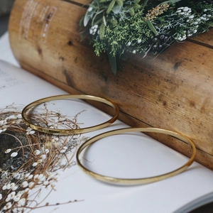 Polished 18K gold-plated titanium steel minimalist slim bangles on a lifestyle background