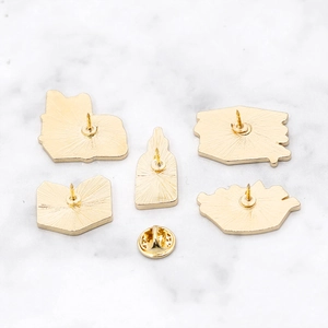 Macro view of gold metal pin back bases and butterfly clutch on marble background