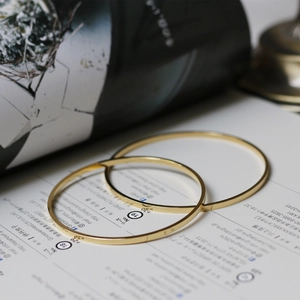 Minimalist 18K gold plated titanium steel thin bangles stacked on a lifestyle background