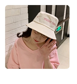 Detail view of the pink embroidered letters on a cream white chenille bucket hat