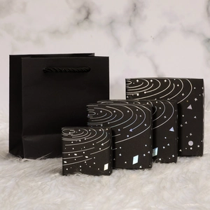 Black starry gift box set with silver foil pattern on marble and plush background