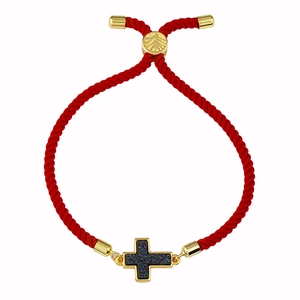 Dettaglio del bracciale in corda rossa intrecciata con ciondolo a croce dorata e chiusura