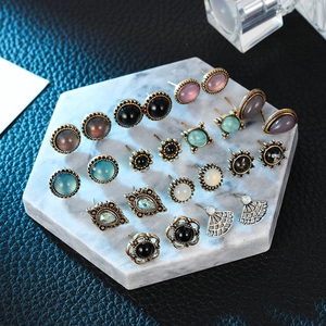Flat lay of vintage stud earring set with cat-eye resin and pearls on marble base