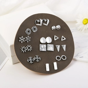 Set of 12 pairs of silver-colored geometric stud earrings on brown leather mat