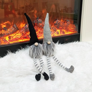 Close-up of two long-legged Christmas gnomes with knit hats on a white rug by a fireplace