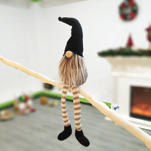 Gnome figurine with long striped legs sitting on a wooden branch for Christmas decor
