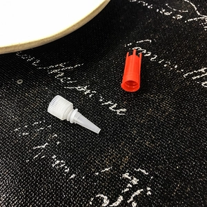 Close-up of red screw cap and white precision nozzle for jewelry repair glue bottles