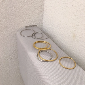 Macro shot showing gold and silver hoop earrings in various sizes on a textured surface