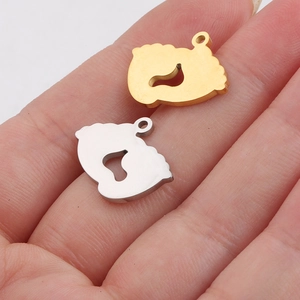 Polished stainless steel baby feet pendants in gold and silver held in palm for size