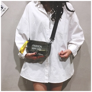 Detail of grey transparent PVC mini crossbody bag worn with fashion lettering on white shirt
