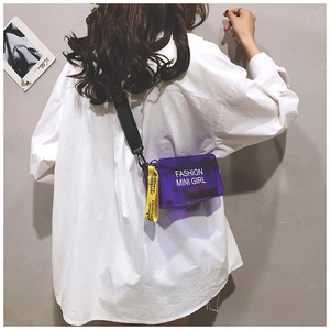 Detail view of purple transparent PVC mini crossbody bag worn by model on white shirt
